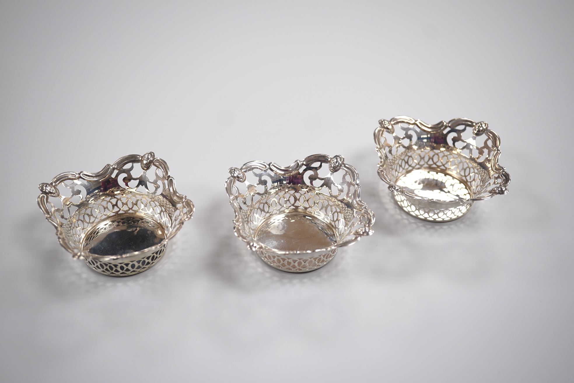 A group of small silver including a modern mounted wine coaster by M C Hersey & Son Ltd, diameter 12.6cm, a set of three George V nut dishes, one other silver nut dish, two pairs of salts including cauldron by William Hu